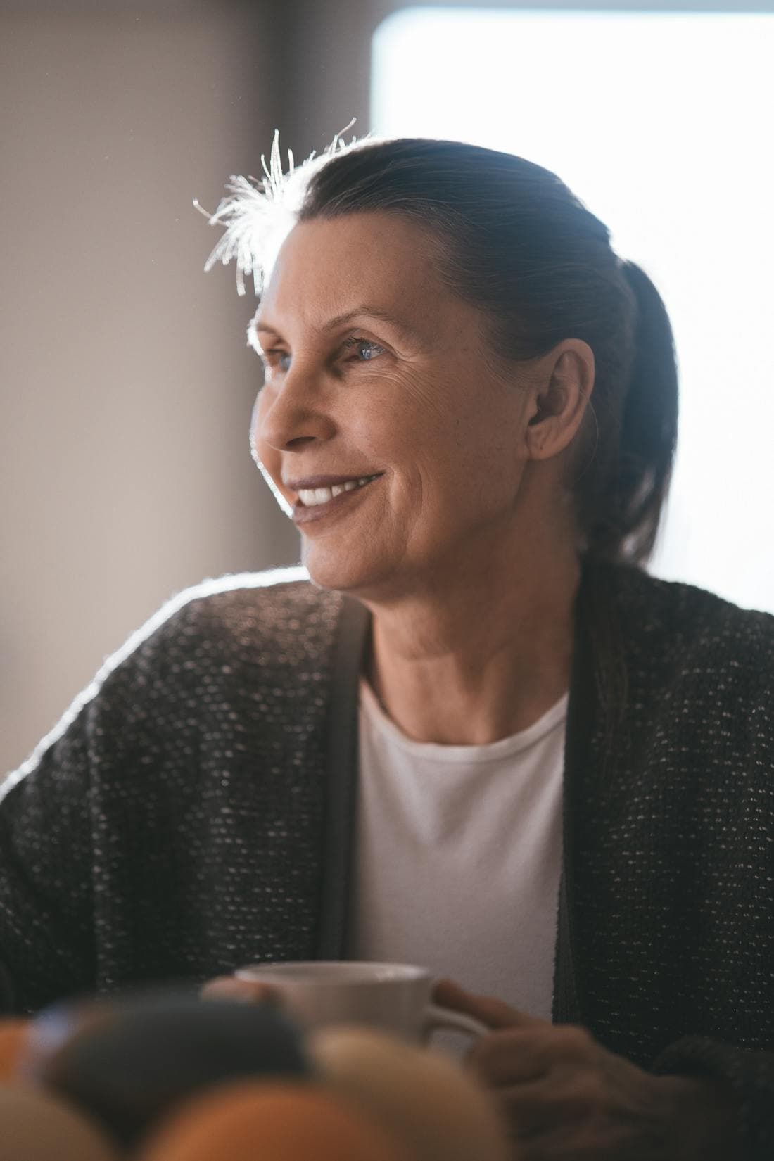Mulher tomando um café tranquilo em casa, perto da janela